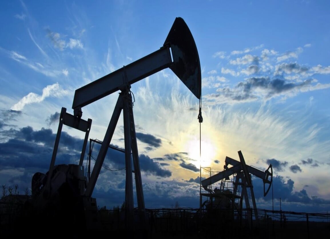 An oil rig with a blue sky as the sun is setting.